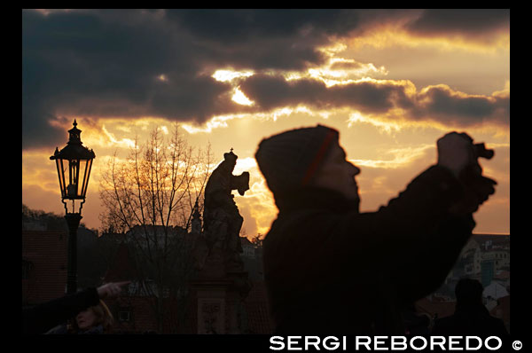 Fotografiant al vespre al pont de Carles. Praga. El Pont de Carles és el monument més famós de Praga i comunica la Ciutat Vella (Staré M? Sto) amb la Ciutat Petita (Malá Strana). Amb més de 500 metres de llarg i 10 d'ample, el Pont de Carles tenir al seu dia 4 carrils destinats al pas de carruatges. Actualment és peatonal. Pont de Carles a l'alba El Pont de Carles rep el seu nom del seu creador, Carles IV, que va posar la primera pedra en 1357 per substituir el pont de Judit, que es va destruir per una inundació. Les estàtues del pont de Carles Al llarg del pont trobareu 30 estàtues situades a banda i banda d'aquest, moltes de les quals són còpies ja que les originals es troben al Museu Nacional de Praga i en Vyšehrad i van ser construïdes a principis del segle XVIII . La primera estàtua que es va afegir en 1683 va ser la de Sant Joan Nepomuceno. Juan Nepomuceno va ser llençat al riu a 1393 per ordre de Wenceslao IV i al segle XVIII va ser santificat. Demana un desig Al lloc des d'on va ser llançat a l'aigua Sant Joan Nepomuceno es troba la seva estàtua. Es diu que qui demana un desig posant la mà esquerra en la representació del seu martiri (a la base de l'estàtua), aquest li serà concedit. Creuant el pont trobarem, a més de les estàtues, puestecillos i artistes intentant guanyar-se la vida.