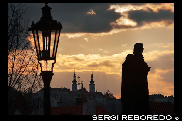 Estatuas al atardecer en el Puente de Carlos. Praga.  El puente de Carlos, es el monumento más célebre de Praga, y comunica la Ciudad Vieja y Malá Strana. Aunque actualmente es peatonal, en su tiempo podía dar paso a cuatro carruajes en línea. Hoy día, muchas de las estatuas que alberga son copias, ya que las originales se consercan en el Lapidarium del Museo Nacional de Praga. Hasta 1741, este puente era el único que cruzaba el Moldava. Mide 520 m de largo y se hizo con bloques de piedra arenisca, reforzada, según se cree, añadiendo huevos al mortero. Lo encargo Carlos IV en 1357 para sustituir al puente Judit, destruido por las inundaciones y se debe a Peter Parler. Su primera estatua fue la de Juan Nepomuceno, inspirada en la estatuta de Benini del puente Sant'Angelo de Roma, ya que Juan de Neponucemo fue arrojado del puente por orden de Wenceslao IV en 1393. En 1648 los sucesos destrozaron parte del puente y en 1890 una inundación destruyó tres ojos del puente. Esta es la lista de las 30 estatuas que aparecen en el puente de Carlos: San Wenceslao, 1858 Cristo entre los Santos Cosme y Damián, 1709 San Juan de Mata, San Félix de Valois y el beato Iván, 1714 San Vito, 1714 San Adalberto, 1709 San Felipe Benzi, 1714 Santa Lutgarda, 1710 San Cayetano, 1709 San Juan Nepomuceno, 1683 San Agustín, 1708 San Nicolás Tolentino, 1708 San Judas Tadeo, 1708 Santos Vicente Ferrer y Procopio, 1712 San Francisco de Asís con dos ángeles, 1855 San Antonio de Padua, 1707 Santa Ludmila, 1710 Santos Norberto, Wenceslao y Segismundo, 1853 San Francisco de Borja, 1710 San Juan Bautista, 1857 San Cristobal, 1857 Santos Cirilo y Metodio San Francisco Javier, 1711 Santa Ana, 1707 San José, 1854 Crucifixión, siglo XVII Pietà, 1859 Santas Bárbara, Margarita e Isabel La Virgen, Santo Domingo y Santo Tomás, 1708 La Virgen y San Bernardo, 1709 