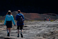 Una pareja haciendo un trekking por encima de la lava del Volcan Pitón de la Fournaise. La isla de Reunión esta forma por dos grandes estrato volcanes de composición principalmente basálticos, yuxtapuestos sobre el fondo oceánico y parcialmente emergidos: el Piton des Neiges al noroeste, más antiguo y extinto desde hace 20.000 años, culmina a 3070 m. El Piton de la Fournaise es un volcán activo que se formó sobre el lado sureste del primero y alcanza los 2631m de altitud. El volumen total emergido de la isla representa 0,8x103 km3, a sea 1/32 del volumen total de la estructura global. Si se tiene en cuenta el volumen oculto en la zona de pliegue monoclinal de la placa, la parte emergida no representa que un centésimo del volumen total. Las primeras manifestaciones eruptivas sobre el fondo del océano a 4000 m profundidad son estimadas ocurrieron hace 4 a 5 mi; el Pitón des Neiges alcanza hoy alrededor de 7000 m de altura desde el fondo del océano.