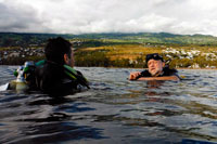 Excelsul Diving Club. Bussejadors apunt de submergir-se en les aigües de Reunió. Reunió és una illa francesa d'uns 200 km. l'oest de la Illa Maurici. El corall forma un escull d'uns 15 km. a l'oest i al sud de l'illa. Saint-Gilles-les-Bains i Saint-Leu, tant a la part oest de l'illa, són els millors llocs per bussejar. Saint-Gilles-les-Bains és una ciutat petita platja amb una gran varietat de bars i restaurants i més bonica platja de sorra blanca de l'illa, Boucan Canot. Moltes operacions de busseig es troben aquí i tots ells se centren principalment en els esculls. Els peixos pelàgics són poc freqüents, però petits peixos d'escull són abundants. Canó és un lloc de busseig bo, ideal per a principiants. Passe de Trois Bassin és un altre lloc on es pot bussejar paret. El naufragi Navarra és una immersió profunda emocionant. La Navarra és un vaixell de la llagosta 150 peus que es va enfonsar allà. Saint-Leu és un lloc de surf de renom mundial, que també compta amb esplèndides immersions de paret i els esculls. En Pointe Au Sel vostè tindrà l'oportunitat d'observar espècies pelàgiques. Maison Verte és un gran jardí de corall amb abundant vida marina. Els taurons martell es poden observar entre els mesos d'octubre i novembre.