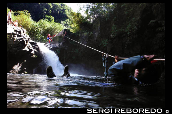 Aymeric. Barranquisme al Rio Langevin, al costat de la cascada de Grand Galet. L'especial orografia del terreny va propiciar la formació d'innombrables les, (nom local mitjançant el qual es defineixen els torrents de muntanya) i de Ravines (torrents). Amb més de 70 barrancs equipats, a més d'innombrables vies d'escalada, Reunion és sense cap dubte un referent a nivell mundial per als amants del descens de barrancs. Les característiques de la major part de descensos, difereixen bastant dels barrancs que tenim per les nostres latituds. En Reunion el principal protagonista és el desnivell, tant total com parcial, ja que són habituals les grans cascades, com les de Ravine Blanche, on l'aigua inicialment es precipita a través de sengles cascades de 440 i 310 metres d'alçada respectivament. O també amb desnivells acumulats que sobrepassen els 1.000 metres, com és el cas del Bras Magazín, amb 1.140 metres. Les aproximacions i els retorns dels barrancs també són una veritable aventura, ja que en moltes ocasions, especialment en els canons del Circ de Salazie, discorren a través d'una espessa vegetació, salvant trams que arriben a ser verticals amb l'ajuda de cordes fixes, escales d'alumini, o simplement fent el Tarzan per les arrels i les branques dels arbres. Són el que en Reunion s'anomenen Sentiers de canyoneurs (senders de canoners o barranquistes). Nosaltres alucinábamos en pensar en el treball i la dificultat que va haver de portar obrir aquests senders. Prova d'això és que l'obertura del barranc de Rivière des Roches, va suposar amb 14 dies d'expedició, la major obertura de la història del barranquisme. Allà per l'any 1.989 el guia d'alta muntanya francès Pascal Cues, va arribar per primera vegada a Reunion a una expedició de tres setmanes de durada. Pascal va quedar captivat davant l'extraordinari potencial de l'illa, tant és així, que el que inicialment havia de ser una estada de tres setmanes es va convertir en sis mesos ... A ell se li deu el naixement del barranquisme i l'escalada a l'illa i l'obertura d'innombrables descensos com el del Trou de Fer, Takamaka, Ravine Blanche, Fleur Jaunes i un llarg etcètera. Finalment Pascal es va instal · lar a Reunion, fundant diverses empreses de guies: Canyon Reunion, la Compagnie des Guides de la Reunió i Réunion Sensations. Tots els barrancs es poden classificar en tres grans grups, atenent a les seves característiques: els barrancs verds, vermells i blaus. Els barrancs verds es troben situats al Circ de Salazie. Reben aquest nom gràcies a la vegetació exuberant que els envolta i estan molt encaixats. A causa de les dues característiques presenten uns accessos força complexos. Els cingles vermells estan situats al Circ de Cilaos i de Mafate. Deuen el seu nom als innombrables afloraments ferris, que li donen el color vermellós tan característic a la roca. El seu perfil és similar al dels barrancs que trobem per les nostres latituds, concretament als Pirineus. Finalment els barrancs blaus situats a la franja litoral i secs gran part de l'any, presenten una llera poc encaixat i per tant uns accessos relativament senzills.