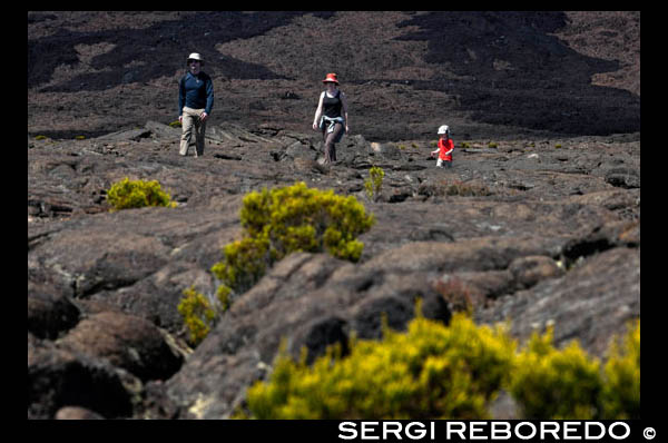 Una familia fent un trekking per sobre de la lava del Volcà Pitó de la Fournaise. És l'únic volcà actiu de l'illa. Les seves erupcions atrauen milers de visitants. Les colades de lava s'estenen fins a la costa est originant un paisatge únic. Al volcà, quan no està actiu, es pot realitzar senderisme. Hi ha diverses rutes marcades. La carretera d'accés al volcà val la pena. Es travessen paratges plens de vegetació adaptada a les condicions d'altitud i humitat (boira constant) que hi ha en aquesta zona. Podreu veure diversos cràters i una zona completament desèrtica anomenada Plaine des Sables a la qual s'arriba després de creuar pel Pas des Sables on val la pena aturar-se a contemplar el paisatge. Abans de visitar el volcà us recomano que feu una parada al poblet de Bourg-Murat on està situada la Maison du Volcan, un Museu on expliquen la formació de l'illa, l'activitat volcànica i les erupcions més importants al llarg de la història de Reunió. Projecten un audiovisual molt interessant.