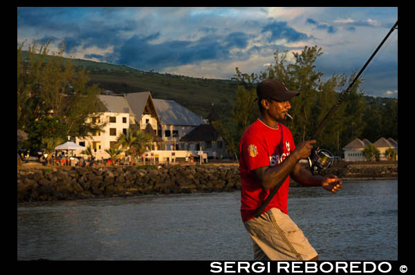 Un pescador en el puerto de Saint Leu. La isla de La Reunión salió del fondo del océano Índico. Los primeros basamentos de la isla se formaron hace unos 67 millones de años, durante el último período de actividad de la dorsal de la Cuenca de las Mascareñas. A la vez entra en actividad un punto caliente y da origen a un inmenso zócalo basáltico, formando el actual Deccan de la India. Mucho más tarde, debido a la lenta deriva de las placas tectónicas, este punto caliente va a perforar el fondo oceánico al este de Madagascar para formar, primero, la isla de Mauricio y después la de Reunión. La Reunión emerge de las aguas hace entre dos millones y medio y tres millones de años. El volcán primitivo y punto culminante de la isla, el piton des Neiges, cesó su actividad hace unos 12000 años. El hecho de haber vaciado su depósito magmático trajo consigo el hundimiento de su techo y el nacimiento de los tres circos o depresiones que lo rodean: Salazie, Cilaos y Mafate, limitados por impresionantes paredones. Sin embargo, antes de acabar su actividad ya habían ocurrido las primeras erupciones del actual piton de la Fournaise (pico del Horno) al sudeste. Tanto el “piton des Neiges” como el “piton de la Fournaise” son volcanes de tipo hawaiano, produciendo fuentes de lava poco violentas. La fluidez de su magma permite a los gases salir fácilmente. La roca emitida es un basalto con numerosos cristales traslúcidos de olivina, de color verde botella. Sobre este material se desarrollan diversos tipos de suelos en función del relieve y el clima. La isla se hunde más de 4000 m. bajo el nivel del mar y en el fondo del océano la circunferencia total del volcán es de 700 a 800 km. El volcán de la Fournaise tiene una actividad volcánica intensa y erupciona, de media, una vez al año. Cada vez que eso ocurre, miles de personas se acercan con sus coches al punto desde donde es visible la erupción, formándose enormes colas en las carreteras. Hasta hace muy poco las autoridades no tomaban excesivas medidas restrictivas para evitar que la gente se acercara a las lenguas de lava y se formaban auténticas fiestas y “barbacoas” sobre la misma. Hoy en día los accesos están mucho más controlados.