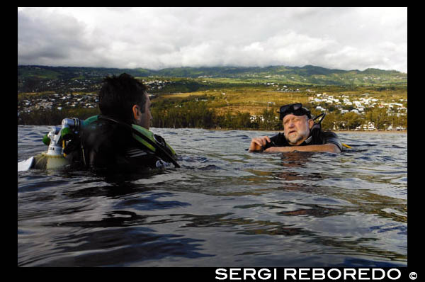 Excelsul Diving Club. Bussejadors apunt de submergir-se en les aigües de Reunió. Reunió és una illa francesa d'uns 200 km. l'oest de la Illa Maurici. El corall forma un escull d'uns 15 km. a l'oest i al sud de l'illa. Saint-Gilles-les-Bains i Saint-Leu, tant a la part oest de l'illa, són els millors llocs per bussejar. Saint-Gilles-les-Bains és una ciutat petita platja amb una gran varietat de bars i restaurants i més bonica platja de sorra blanca de l'illa, Boucan Canot. Moltes operacions de busseig es troben aquí i tots ells se centren principalment en els esculls. Els peixos pelàgics són poc freqüents, però petits peixos d'escull són abundants. Canó és un lloc de busseig bo, ideal per a principiants. Passe de Trois Bassin és un altre lloc on es pot bussejar paret. El naufragi Navarra és una immersió profunda emocionant. La Navarra és un vaixell de la llagosta 150 peus que es va enfonsar allà. Saint-Leu és un lloc de surf de renom mundial, que també compta amb esplèndides immersions de paret i els esculls. En Pointe Au Sel vostè tindrà l'oportunitat d'observar espècies pelàgiques. Maison Verte és un gran jardí de corall amb abundant vida marina. Els taurons martell es poden observar entre els mesos d'octubre i novembre.