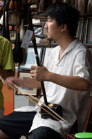 Tocar l'instrument de música tradicional al casc antic de Xangai. Instrument de corda anomenat Sanxian. El sanxian és un llaüt xinès - 01:00 fretless de tres cordes arrencar instrument musical. Té una llarga diapasó, i el cos es fa tradicionalment a partir de pell de serp estirada sobre un ressonador rectangular arrodonida. Es fabrica en diverses mides per a diferents propòsits i en el segle 20 una versió de quatre cordes també es va desenvolupar. El sanxian nord és generalment més grans, en al voltant de 122 cm de longitud, mentre que les versions del sud de l'instrument són generalment prop de 95 cm de longitud. El sanxian té un to una mica percussiu sec i volum alt similar al banjo.