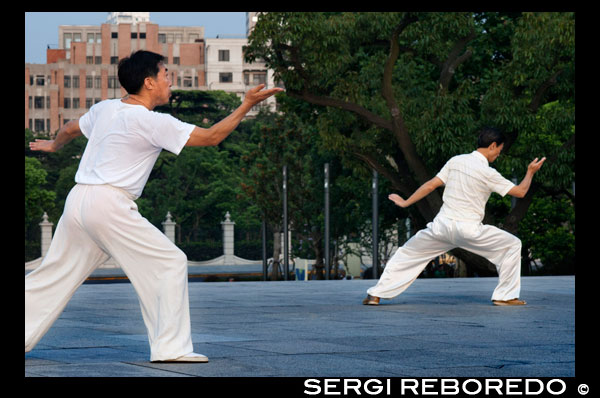 China, Shanghai, morning tai chi exercise on The Bund. Shanghi Bund : Early morning tai chi exercises with swords on the Bund in Shanghai China. The best taichi lessons I've had were from an old guy who practiced outside at 7am every morning. I learned 4 excellent techniques that I still use in my MMA training on a regular basis- a method of catching a kick and throwing your opponent, redirecting a straight punch and countering in the same motion, countering double underhooks with a throw, and escaping a shoulder lock while setting up your own.  It's a really fascinating martial art because every one of those dance like movements represents a simple practical fighting technique or strategy, but it's hard to see how the movements translate into combat applications without a master of the art demonstrating it. But either way even without a kungfu master, the forms themselves are great low impact exercise that you can find everywhere in the city for free every morning.   Most of the old folks in the parks won't mind if you tag along, just show up early and make sure to ask first if it's okay to join them.  The Bund (which means the "Embankment") refers to Shanghai's famous waterfront running along the west shore of the Huangpu River, forming the eastern boundary of old downtown Shanghai. Once a muddy towpath for boats along the river, the Bund was where the foreign powers that entered Shanghai after the Opium War of 1842 erected their distinct Western-style banks and trading houses. From here, Shanghai grew into Asia's leading city in the 1920s and 1930s, a cosmopolitan and thriving commercial and financial center. Many of the awesome colonial structures you see today date from that prosperous time and have become an indelible part of Shanghai's cityscape. After 1949, the street came to symbolize Western dominance over China and was shuttered. 