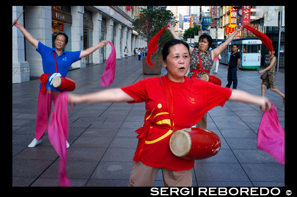 China, Shanghai, Nanjing Road, tai chi, exercises, people before opening the shops. Evening tai chi group exercising on Nanjing Dong Lu, Shanghai. Nanjing Road (Chinese: ???; pinyin: Nánj?ng Lù) is the main shopping street of Shanghai, China, and is one of the world's busiest shopping streets. It is named after the city of Nanjing, capital of Jiangsu province neighbouring Shanghai. Today's Nanjing Road comprises two sections, Nanjing Road East and Nanjing Road West. In some contexts, "Nanjing Road" refers only to what was pre-1945 Nanjing Road, today's Nanjing Road East, which is largely pedestrianised. Before the adoption of the pinyin romanisation in the 1950s, its name was rendered as Nanking Road in English. The history of Nanjing Road can be traced back to the year 1845. At that time it was called “Park Lane”, which stretched from the Bund to He’nan Road. In 1854, it was extended to Zhejiang Road, and eight years later, once more extended to Xizang Road. In 1862, it was named formally “Nanking Road” by the Municipal Council, which administered the International Settlement. In Chinese it was usually referred to as the Main Road (???). Around 1930 it was a bustling street with at least one reported casino (probably at nr. 181).[citation needed] In 1943 the International Settlement was annulled, and after World War Two the government changed its name from Nanking Road to "East Nanjing Road", meanwhile they also renamed the former Bubbling Well Road "West Nanjing Road", and the general name of the two roads became "Nanjing Road", comprising five kilometres total length.