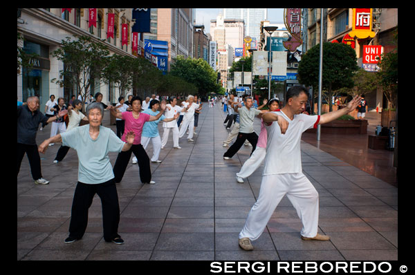 China, Shanghai, Nanjing Road, tai chi, exercises, people before opening the shops. Evening tai chi group exercising on Nanjing Dong Lu, Shanghai. Nanjing Road (Chinese: ???; pinyin: Nánj?ng Lù) is the main shopping street of Shanghai, China, and is one of the world's busiest shopping streets. It is named after the city of Nanjing, capital of Jiangsu province neighbouring Shanghai. Today's Nanjing Road comprises two sections, Nanjing Road East and Nanjing Road West. In some contexts, "Nanjing Road" refers only to what was pre-1945 Nanjing Road, today's Nanjing Road East, which is largely pedestrianised. Before the adoption of the pinyin romanisation in the 1950s, its name was rendered as Nanking Road in English. The history of Nanjing Road can be traced back to the year 1845. At that time it was called “Park Lane”, which stretched from the Bund to He’nan Road. In 1854, it was extended to Zhejiang Road, and eight years later, once more extended to Xizang Road. In 1862, it was named formally “Nanking Road” by the Municipal Council, which administered the International Settlement. In Chinese it was usually referred to as the Main Road (???). Around 1930 it was a bustling street with at least one reported casino (probably at nr. 181).[citation needed] In 1943 the International Settlement was annulled, and after World War Two the government changed its name from Nanking Road to "East Nanjing Road", meanwhile they also renamed the former Bubbling Well Road "West Nanjing Road", and the general name of the two roads became "Nanjing Road", comprising five kilometres total length.