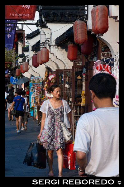 Compres botigues al voltant de petits a la Ciutat Vella, Shanghai, Xina. La ciutat vella de Xangai, Shangh? I L? O Chengxi? Ng, també conegut anteriorment com la ciutat xinesa, és el nucli urbà tradicional de Xangai, Xina. El seu límit es definia per una muralla defensiva. La Ciutat Vella va ser el seient de comtat per l'antic comtat de Xangai. Amb l'adveniment de les concessions estrangeres a Xangai, la ciutat vella es va convertir en només una part del nucli urbà de Xangai, però va continuar en les dècades per ser la seu de l'autoritat de la Xina a Xangai. Les característiques notables inclouen el Temple del Déu de la Ciutat, situat al centre del nucli antic i està connectat amb el Jardí Yuyuan. Amb l'excepció de dues seccions curtes, les parets van ser demolides el 1912, i una àmplia avinguda circular construïda sobre l'antiga muralla i el fossat: la meitat sud es va anomenar el "Zhonghua Road" i la meitat nord de la "Minguo Road" (junts fent dalt "Zhonghua Minguo", o "República de la Xina" en xinès). (La meitat nord va passar a cridar-se "Renmin Road" ("Camí del Poble") en 1950 pel nou govern comunista de Xangai). La Ciutat Vella va ser durant dècades en gran part confrontant amb l'antic Districte Nanshi, que ara és part de districte de Huangpu.