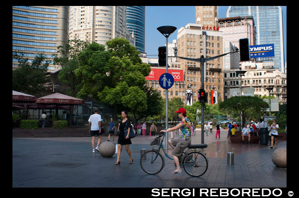 Las mujeres con una bicicleta en Nanjing Road, Shanghai. Nanjing Road (chino: ???, pinyin:? Nánj ng LU) es la principal calle comercial de Shanghai, China, y es una de las calles comerciales más activas del mundo. Lleva el nombre de la ciudad de Nanjing, capital de la provincia de Jiangsu vecina Shanghai. Nanjing Road de hoy consta de dos secciones, Nanjing Road East y West Nanjing Road. En algunos contextos, "Nanjing Road" se refiere sólo a lo que era pre-1945 Nanjing Road, la actual Nanjing Road East, que es en gran parte peatonal. Antes de la adopción de la romanización pinyin en la década de 1950, su nombre fue traducido como Nanking Road en Inglés. La historia de Nanjing Road se remonta al año 1845. En ese momento se le llamó "Park Lane", que se extendía desde el Bund a He'nan Road. En 1854, se amplió a Zhejiang Road, y ocho años más tarde, una vez más extendida a Xizang Road. En 1862, fue nombrado formalmente "Nanking Road" por el Consejo Municipal, que administra el Acuerdo Internacional. En chino se refiere generalmente como la carretera principal (???). Alrededor de 1930 fue una bulliciosa calle con al menos un casino reportado (probablemente en el nr. 181). [Cita requerida] En 1943 el Acuerdo Internacional fue anulado, y después de la Segunda Guerra Mundial, el gobierno cambió su nombre de la calle Nanking a "East Nanjing Road ", por su parte, también cambió el nombre del ex Calle del Pozo Burbujeante" West Nanjing Road ", y el nombre general de los dos caminos se convirtió en" Nanjing Road ", que comprende cinco kilometros de longitud total.