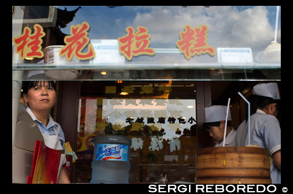 Restaurante en el casco antiguo, Shanghai. Bandejas de vapor de bambú con opciones de dim sum en un pequeño restaurante en la antigua ciudad de Dios Templo en Shanghai Old Street. Lado de la carretera chino Dumpling o Dim Sum Stall en la Ciudad Vieja, Shanghai, China. Xiaolongbao es un tipo de bollo al vapor (baozi) de la región de Jiangnan de China, especialmente asociado con Shanghai y Wuxi. Se prepara tradicionalmente en xiaolong, pequeñas cestas humeantes de bambú, lo que les da su nombre. Xiaolongbao se refiere a menudo como una especie de "bola de masa", pero no se debe confundir con albóndigas británicos o de estilo americano ni con jiaozi chino. Del mismo modo, se consideran una especie de "bola de masa de la sopa", pero no deben confundirse con otras variedades más grandes de tang bao. En Shanghai, también se conocen a veces como SiOH-lon meu-doe o estilo xiaolong xiaolongbao estilo mantous.Shanghai originado en Nanxiang, un suburbio de Shanghai, en el distrito de Jiading. El inventor de xiaolongbao los vendió en su primera tienda en Nanxiang junto al parque notable de la ciudad, Guyi Garden. A partir de ahí el xiaolongbao ampliado en el centro de Shanghai y outward.Two restaurantes xiaolongbao especialistas tienen una muy larga historia. Uno es Nanxiang mantou Dian (Nanxiang Bollo Shop), que deriva de la tienda original en Nanxiang pero ahora se encuentra en la zona del Jardín Yu. Es famosa por sus bollos de cangrejo rellenos de carne. El otro es Gulong restaurante, en el sitio original junto a Guyi Garden en Nanxiang.