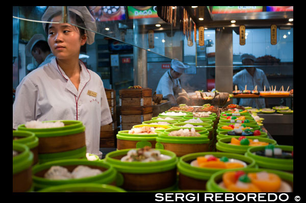 Restaurante en el casco antiguo, Shanghai. Bandejas de vapor de bambú con opciones de dim sum en un pequeño restaurante en la antigua ciudad de Dios Templo en Shanghai Old Street. Lado de la carretera chino Dumpling o Dim Sum Stall en la Ciudad Vieja, Shanghai, China. Xiaolongbao es un tipo de bollo al vapor (baozi) de la región de Jiangnan de China, especialmente asociado con Shanghai y Wuxi. Se prepara tradicionalmente en xiaolong, pequeñas cestas humeantes de bambú, lo que les da su nombre. Xiaolongbao se refiere a menudo como una especie de "bola de masa", pero no se debe confundir con albóndigas británicos o de estilo americano ni con jiaozi chino. Del mismo modo, se consideran una especie de "bola de masa de la sopa", pero no deben confundirse con otras variedades más grandes de tang bao. En Shanghai, también se conocen a veces como SiOH-lon meu-doe o estilo xiaolong xiaolongbao estilo mantous.Shanghai originado en Nanxiang, un suburbio de Shanghai, en el distrito de Jiading. El inventor de xiaolongbao los vendió en su primera tienda en Nanxiang junto al parque notable de la ciudad, Guyi Garden. A partir de ahí el xiaolongbao ampliado en el centro de Shanghai y outward.Two restaurantes xiaolongbao especialistas tienen una muy larga historia. Uno es Nanxiang mantou Dian (Nanxiang Bollo Shop), que deriva de la tienda original en Nanxiang pero ahora se encuentra en la zona del Jardín Yu. Es famosa por sus bollos de cangrejo rellenos de carne. El otro es Gulong restaurante, en el sitio original junto a Guyi Garden en Nanxiang.