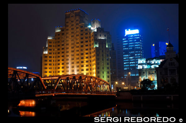 Xangai pont Jardí. Suzhou Creek, Waibaidu (Jardí) Bridge, il·luminat a la nit, Shanghai, Xina. El pont Waibaidu, Waibaidu Qiao, anomenat el pont del jardí en anglès, és el primer pont completament d'acer, i l'únic exemple supervivent d'un pont de braguer camell, a la Xina. El quart pont exterior construït en el seu lloc des de 1856, al d'aigües avall de la desembocadura del riu Suzhou, a prop de la seva confluència amb el riu Huangpu, al costat del Bund al centre de Xangai, que connecta els districtes de Huangpu i Hongkou, es va obrir el pont actual el 20 de gener de 1908. Amb la seva rica història i un disseny únic del pont Waibaidu és un dels símbols de Xangai. La seva imatge moderna i industrial pot considerar com a pont símbol de la ciutat. El 15 de febrer de 1994, el Govern Municipal de Xangai va declarar el pont un exemple de l'arquitectura del Patrimoni, i una de les estructures més notables a Xangai. En una metròpoli en constant canvi, el Pont Waibaidu segueix sent una atracció popular, i una de les poques constants en l'horitzó de la ciutat. Abans dels ponts van ser construïts sobre el Suzhou Creek (llavors conegut com el riu Wusong), els ciutadans van haver d'utilitzar una de les tres creus en ferri: un a prop Zhapu Road, un a Jiangxi Road, i un prop de la desembocadura del riu Suzhou. Aquests encreuaments (du en xinès) eren l'única manera de travessar el riu, fins a la construcció d'una resclosa construïda en la dinastia Ming, més tard conegut com "Old resclosa", on es troba l'actual pont de Fujian Road. Durant la dinastia Qing, es va construir un altre pont resclosa ("Nova Esclusa") durant el regnat de l'emperador Yongzheng (1723-1735), a prop de la ubicació del pont Datong Camí d'avui. Amb Xangai convertir-se en un port internacional del comerç a través del Tractat de Nanjing a 1842, i les potències estrangeres sent atorgat concessions a la ciutat, el trànsit entre els dos costats del riu Suzhou es va disparar a la dècada de 1850, l'augment de la necessitat d'un pont prop de la desembocadura del riu.