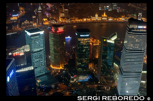 Vistas desde la Torre World Finance, Shanghai, ChinaCityscape, vista del río Huangpu, el Bund, Puxi y financiero de la ciudad, Shanghai, China. La palabra "bund" significa un terraplén o un muelle terraplenado. La palabra proviene de la palabra persa banda, a través de indostánica, lo que significa un terraplén, dique o presa (un cognado de términos en inglés "atar", "bonos" y "banda", y la palabra alemana "Bund", etc.). Por tanto, se nombra después de las federaciones / diques en Bagdad a lo largo del Tigris, cuando los Judios Baghdadi como la prominente familia Sassoon establecieron sus negocios en Shanghai en el siglo 19 y construido en gran medida en el Bund en el Huangpo. En estas ciudades portuarias chinas, el término Inglés llegó a significar, sobre todo, el muelle con dique a lo largo de la orilla. En Inglés, "Bund" se pronuncia para rimar con "fondo". Existen numerosos sitios en la India, China y Japón, que son llamados "bonos" (por ejemplo, el Yokohama Bund). Sin embargo, "El Bund", sin reservas en cuanto a la ubicación, por lo general se refiere a este tramo de la orilla del río terraplenado en Shanghai. El nombre chino para el Bund no está relacionada en significado: significa literalmente el "banco de exterior", en referencia al río Huangpu, porque esta parte de la orilla del río se encuentra río abajo de la zona de "banco de interior" al lado de la antigua ciudad amurallada de Shanghai. El Shanghai Bund tiene docenas de edificios históricos, que bordean el río Huangpu, que numerosos bancos una vez alojados y casas comerciales del Reino Unido, Francia, Estados Unidos, Italia, Rusia, Alemania, Japón, los Países Bajos y Bélgica, así como el consulados de Rusia y Gran Bretaña, un periódico, el Club de Shanghai y el Club masónico. El Bund se encuentra al norte de la antigua ciudad amurallada de Shanghai. Al principio fue un asentamiento británico; más tarde, los asentamientos británicos y estadounidenses se combinaron en el Acuerdo Internacional. Magníficos edificios comerciales en el estilo Beaux Arts surgieron en los años alrededor de la vuelta del siglo 20 como el Bund se convirtió en un importante centro financiero de Asia Oriental. Directamente al sur, y al noreste de la antigua ciudad amurallada, el ex Bund francés (el quai de Francia, parte de la Concesión Francesa de Shanghái) era de un tamaño comparable al Bund pero funcionó más como un trabajo al puerto.