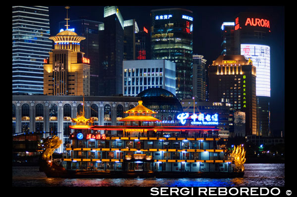 Pudong Skyline, por la noche, Shanghai, China. Horizonte de Pudong, visto desde el Bund, con Torre de marca de la Perla Oriental y la torre Jin Mao, Shangai, China. La palabra "bund" significa un terraplén o un muelle terraplenado. La palabra proviene de la palabra persa banda, a través de indostánica, lo que significa un terraplén, dique o presa (un cognado de términos en inglés "atar", "bonos" y "banda", y la palabra alemana "Bund", etc.). Por tanto, se nombra después de las federaciones / diques en Bagdad a lo largo del Tigris, cuando los Judios Baghdadi como la prominente familia Sassoon establecieron sus negocios en Shanghai en el siglo 19 y construido en gran medida en el Bund en el Huangpo. En estas ciudades portuarias chinas, el término Inglés llegó a significar, sobre todo, el muelle con dique a lo largo de la orilla. En Inglés, "Bund" se pronuncia para rimar con "fondo". Existen numerosos sitios en la India, China y Japón, que son llamados "bonos" (por ejemplo, el Yokohama Bund). Sin embargo, "El Bund", sin reservas en cuanto a la ubicación, por lo general se refiere a este tramo de la orilla del río terraplenado en Shanghai. El nombre chino para el Bund no está relacionada en significado: significa literalmente el "banco de exterior", en referencia al río Huangpu, porque esta parte de la orilla del río se encuentra río abajo de la zona de "banco de interior" al lado de la antigua ciudad amurallada de Shanghai. El Shanghai Bund tiene docenas de edificios históricos, que bordean el río Huangpu, que numerosos bancos una vez alojados y casas comerciales del Reino Unido, Francia, Estados Unidos, Italia, Rusia, Alemania, Japón, los Países Bajos y Bélgica, así como el consulados de Rusia y Gran Bretaña, un periódico, el Club de Shanghai y el Club masónico. El Bund se encuentra al norte de la antigua ciudad amurallada de Shanghai. Al principio fue un asentamiento británico; más tarde, los asentamientos británicos y estadounidenses se combinaron en el Acuerdo Internacional. Magníficos edificios comerciales en el estilo Beaux Arts surgieron en los años alrededor de la vuelta del siglo 20 como el Bund se convirtió en un importante centro financiero de Asia Oriental. Directamente al sur, y al noreste de la antigua ciudad amurallada, el ex Bund francés (el quai de Francia, parte de la Concesión Francesa de Shanghái) era de un tamaño comparable al Bund pero funcionó más como un trabajo al puerto.