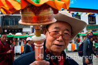 Pelegrins al voltant del temple Jokhang. Lhasa. Cada dia milers de tibetans resen i canten pregàries fent el que ells anomenen la kora al voltant del temple Jokhabg. El temple de Jokhang és el principal temple del Budisme Tibetà a Lhasa. Està situat al voltant de quilòmetre i mig del Palau de Potala immers en el barri amb més activitat de la ciutat. Sens dubte impressiona recórrer el camí que porta al Temple. En la seva entrada principal hi ha una plaça on normalment s'estableix un mercat en el qual es poden adquirir tot tipus de records, roba o art de la regió, de fet està ple de botigues que fan referència a l'art Tibetà.