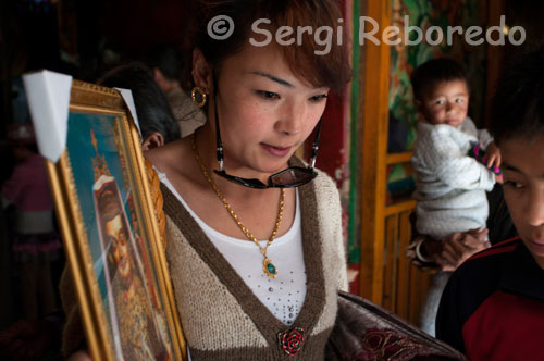 A woman with a picture of a deity out of Tsepak Lhakhang Monastery. Lhasa. Women make a procession around the temple to ask the god of longevity (Cherisi chepal) have a good birth, or elderly people to pray.