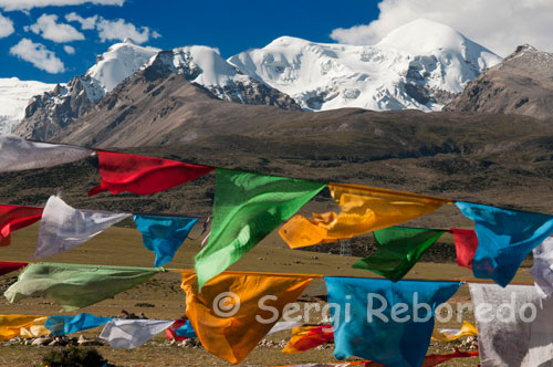 Prayer flags at the base of Mount Nyenchen Tanglha of 7111 meters high. Tibetan prayer flags flutter over the whole world of Tibetan culture. A typical prayer flag in its central image is a horse who carries on his back the Three Jewels in flames. This horse is known as the Horse Wind and flags gives its name in Tibetan "Lung-Ta." The three jewels symbolize the Buddha (the state of enlightenment), dharma (Buddhist teachings) and Sangha (the Buddhist community).