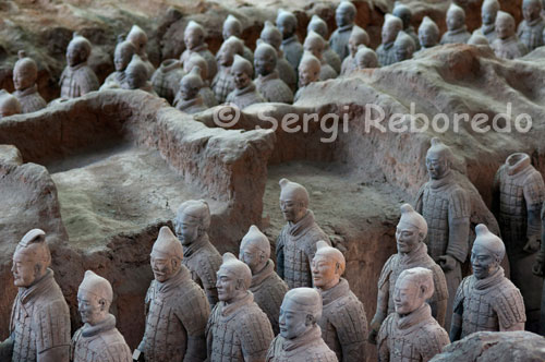 Plano general de algunas de las figuras de los Guerreros de Xian. Cuando uno llega a la fosa número uno, le invade un silencio interior, muestra del asombro al contemplar en perspectiva las 6.000 figuras de guerreros, carros y caballos de terracota dispuestos en posición de batalla y alineados hacia el extremo oriental. Los arqueros cubren las zonas más meridionales aunque también ocupan las tres primeras líneas de fuego junto a los ballesteros, a continuación se disponen los carros arrastrados por cuatro caballos y un auriga y defendidos por batallones de guerreros. Posteriormente, aparece el grueso del ejército dispuesto en 36 hileras y armados con lanzas, hachas, puñales, espadas y ballestas. Las figuras están esculpidas en terracota a un tamaño natural de entre 1’76 y 1’82 metros, modelados de uno a uno probablemente a imagen y semejanza del ejército que en aquel momento servía al emperador Qin Shi Huang.