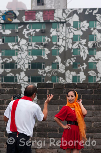 Turistas chinos fotografiándose en la parte superior de la muralla de Xi´an.La Muralla de Xian es la mayor muralla interior que hay en una ciudad de China. Con casi 14 kilómetros de longitud; rodea completamente con una forma cuadrada al espacio que ocupa la antigua ciudad de Xian.Cuando llegamos a la muralla; nos impresionan sus enormes dimensiones. Tiene una altura de 12 metros y en lo alto; una anchura de 12; a 14 metros. De esta forma; al llegar a lo alto del muro por unas anchas escaleras de la puerta sur que se abre en la muralla; nos encontramos ante lo que podría ser incluso una carretera.