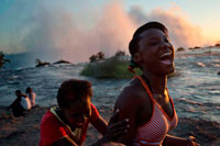 Turistas nacionales visitan las Cataratas Victoria. Victoria Falls es una ciudad en la parte occidental de Zimbabwe, al otro lado de la frontera de Livingstone, Zambia, Botswana y cerca. La ciudad se encuentra justo al lado de las cataratas. Ellos son la principal atracción, pero este popular destino turístico ofrece dos aventureros y turistas un montón de oportunidades para una estancia prolongada. El número de turistas están de vuelta a los niveles históricos, con muchos operadores turísticos añadiendo Vic Falls vuelven a sus itinerarios, y esto es fácilmente más concurrido destino turístico de Zimbabue. En respuesta, hay una gran cantidad de una cartelización y la fijación de precios, con precios de alojamiento y actividades sospechosamente altas, a pesar de que los hoteles no están llenos y operadores de actividades que no opera a plena capacidad. Este destino es ahora considerablemente más caro que otros destinos en Zimbabwe. Mosikalamosikala (que significa "el humo que truena")