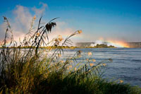 Las vistas de las Cataratas Victoria . Victoria Falls es uno de los dos sitios del Patrimonio Mundial en el río Zambezi . Nuestra oficina local de Victoria Falls es ideal para la gestión de sus reservas a una de las maravillas naturales más célebres del mundo. Planifique su visita en Victoria Falls Safari Network. El río Zambezi fluye ancha y plácida al borde de un labio de basalto de ancho 1.700 mm antes de tomar una 100 metros precipitada zambullida en el abismo atronador , espumosa del Batoka Gorge continuación. Su hoja más grande del mundo de agua que cae. Cataratas Victoria y Livingstone a ambos lados de la caída, facilitan el acceso a los parques nacionales de Zimbabwe , Botswana , Zambia y Namibia , así como Sudáfrica, por safaris regular. El Mosi-oa-Tunya/Victoria Falls y asociadas ocho gargantas escarpadas caras se han formado a través de las posiciones cambiantes de la cascada más de una escala de tiempo geológico. Las gargantas son un excelente ejemplo de la captura de río y las fuerzas erosivas del agua continúan a la escultura los basaltos duros. Estas gargantas toman un curso en zigzag de una distancia de unos 150 kilómetros a lo largo del río Zambezi debajo de las cataratas.