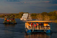 Crucero a lo largo de las Cataratas Victoria a bordo del "African Queen". Otros barcos que navegan en el río Zambezi. Tome un crucero al atardecer por el poderoso río Zambezi. Esta Sundowner crucero te lleva por el río Zambezi para un hermoso viaje!. El crucero Zambezi Puesta del Río es una excelente manera de relajarse y disfrutar de la belleza del río. Usted puede tener la oportunidad de ver una gran variedad de juego, incluyendo hipopótamos, cocodrilos, elefantes e incluso a veces de rinocerontes en su entorno familiar, así como disfrutar de las muchas especies de aves diferentes.