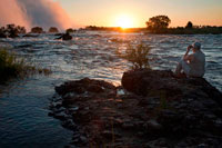 Sunset in the Victoria Falls. The Largest Waterfall in the World. The Victoria Falls have been billed as the Greatest Falling Curtain of Water on this Planet, making it one of the Seven Natural Wonders of the World. The Victoria Falls is considered to be the largest waterfall in the world. They are not the widest waterfall or the highest waterfall but with all dimensions taken into account, including almost the largest flow rate, they are considered to be the biggest curtain of falling water in the world. Surpassing the magnificent Niagara Falls and Iguacu Falls. The Victoria Falls lower mean annual flow rate compared to these two giants is only because of the reduced flow it has during the long dry season of Southern Africa. The Victoria Falls are 1700m wide and are made up of five different “falls”. Four of these are in Zimbabwe and one is in Zambia. They are known as The Devil’s Cataract, Main Falls, Rainbow Falls and Horseshoe Falls in Zimbabwe and the Eastern Cataract in Zambia. Height of Victoria Falls. The Zambezi Rivers' gentle meander through the African landscape is spectacularly interrupted as the river plummets over a knife edge cliff into a narrow chasm below. The height of this chasm varies from 70 m (233ft) to 108m (360ft). 