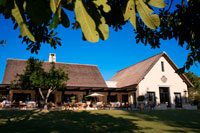 Garden and main entrance of the Royal Livingstone Hotel.  Stretching along the banks of the Zambezi River, consists of a series of 17 colonial-style buildings with deep verandas, set amidst indigenous trees and plants. The main hotel is a sequence of thatch-roofed buildings and incorporates the lounge, restaurant and bar. A stone’s throw away from the mighty Victoria Falls, the Royal Livingstone overlooks the smooth waters just before it plunges over the legendary waterfall creating a permanent water spray. The hotel has already been named as one of the 'Leading Hotels in the World' for its exceptional levels of service, fine dining, comfort and hospitality. It is a five-star colonial style, luxury hotel which has been designed to capture the opulence and elegance of times gone by.  173 spacious guest rooms are located in two-story clusters and are elegantly furnished with en-suite bathrooms which have a roomy shower and a Victorian bath. Each room also has a private verandah, overlooking the Zambezi River or the hotel's rolling lawns. 