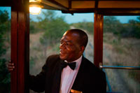 Uno de los trabajadores ferroviarios del tren de lujo Livingstone Express. Cena de lujo se redefine cuando el lugar es el vagón comedor de un tren a vapor de 1920 , en medio de la sabana de Zambia. El Royal Livingstone Express es una empresa conjunta entre Bushtracks África y Sun International . Esta experiencia única es todo incluido y los huéspedes son trasladados de todo Livingstone y las casas de campo de los alrededores de las antiguas oficinas de la línea Mulobezi en la ciudad de Livingstone . Subiendo al tren en una alfombra roja le permitirá disfrutar de esta experiencia que hay que hacer. Cada huésped es recibido personalmente y ofreció una bebida de bienvenida al subir a bordo del carro de la vendimia inmaculada Salón de primera clase. El Royal Livingstone expreso consta de cinco vagones , restaurado por Rohan Vos de Rovos Rail y éstos incluyen dos coches comedor , un coche del club / cocina , alquiler de sala de estar , y un coche de observación y se tira ya sea por una clase 10 N º 156 o un 12 clase N º 204 locomotoras. Una vez que todos los clientes están a bordo del viaje comienza a través suburbio Dambwa hacia el Parque Nacional de Mosi -oa- Tunya , que corre paralela al río Zambezi .