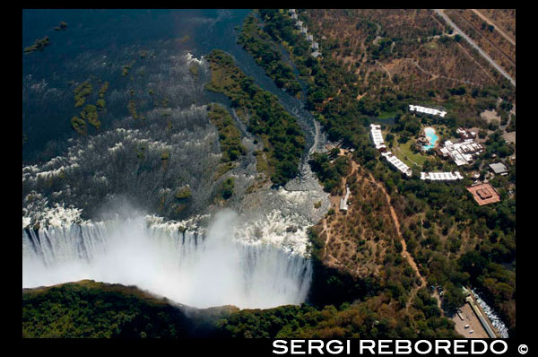 Vistes aèries de les Cascades Victòria. Cascades Victòria presenten una espectacular vista de l'imponent bellesa i la grandesa al riu Zambezi, que forma la frontera entre Zàmbia i Zimbabwe. Va ser descrit pel Kololo tribu que vivia a la zona en la dècada de 1800 com "Mosi-oa-Tunya" - "El fum que trona". En termes més moderns Victoria Falls és coneguda com la major cortina d'aigua que cau al món. Columnes d'aerosol es poden veure des de quilòmetres de distància ja que, en l'apogeu de la temporada de pluges, més de cinc-cents milions de metres cúbics d'aigua per minut cauen en picat sobre la vora, en una amplada de gairebé dos quilòmetres, en un barranc de més de cent metres a continuació. L'àmplia, penya-segat de basalt sobre la qual el tro caigudes, transforma el Zambezi des d'un plàcid riu en un torrent ferotge tall a través d'una sèrie de gorges espectaculars. Davant de les Cascades és una altra gran paret de basalt, aixecant a la mateixa altura i coronada per nebulitzada selva xopa. Un camí al llarg de la vora del bosc ofereix al visitant preparat per enfrontar-se a la tremenda polvorització, amb una sèrie sense precedents de vistes de les Cataractes. Un punt de vista especial és tot el tall de la navalla Bridge, on els visitants poden tenir la millor vista de la cataracta de l'Est i les cataractes principal, així com el Boiling Pot, on el riu es torna i es dirigeix ??cap avall la Batoka Gorge. Altres punts de vista són el pont de les caigudes i l'arbre del lloc d'observació, els quals manen vistes panoràmiques de les cataractes principals.