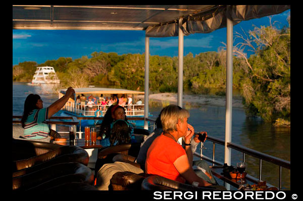 Crucero a lo largo de las Cataratas Victoria a bordo del "African Queen" . Cruceros al atardecer en el río Zambezi en las Cataratas Victoria ver las vainas y los elefantes a veces cruzan el río Zambeze hipopótamo . Los clientes son recogidos de su hotel o albergue a las 15:30 en invierno y de 16:00 horas en los meses de verano y se transfieren al sitio embarcadero. Salidas de Cruceros a las 16:00 horas en invierno y 16:30 en verano. Siguiendo este crucero al atardecer , será trasladado de regreso a su hotel entre las 18:30 hrs y las 19:00 hrs (invierno y verano respectivamente ) . En el embarcadero de huéspedes secundarios son recibidos por una banda tradicional africana antes de firmar el formulario de indemnización estándar. Después de una charla de seguridad y hablar los visitantes abordan el barco safari. Con salida de aguas abajo , serpenteando a través de las islas , los guías le hablarán y describir la flora y la fauna, así como la prolífica vida de aves y vida silvestre. Amantes de las aves serán recompensados ??por los avistamientos como el Finfoot africana , cigüeñas de pico de Open, cigüeñas de pico amarillo y Ibis sagrado . El crucero se lleva a cabo a un ritmo más lento para que pueda disfrutar el ambiente relajado y la belleza del poderoso río Zambezi . Hay aperitivos y bebidas disponibles durante el viaje. El río Zambezi Safari tiene una duración de aproximadamente 2 horas . Al final de los invitados de safari son transferidos de vuelta a su hotel / lodge.