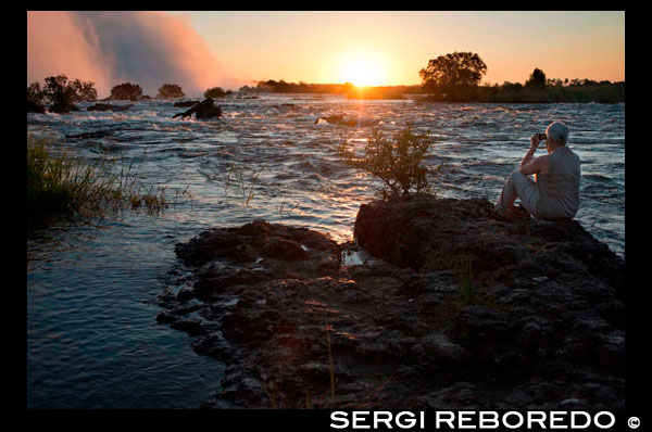 Posta de sol a les Cascades Victòria. La cascada més gran en el món. Les cascades Victòria s'han anunciat com la Cortina de Falling gran d'aigua en aquest planeta, pel que és una de les Set Meravelles Naturals del Món. Les Cataractes Victòria és considerada com la cascada més gran al món. Ells no són la cascada més ampla o la cascada més alta, però amb totes les dimensions que es tenen en compte, entre ells gairebé la velocitat de flux més gran, ells són considerats com el major cortina d'aigua que cau al món. Superant les magnífiques Cascades del Niàgara i les Cascades d'Iguaçú. The Victoria Falls significa menys cabal anual en comparació amb aquests dos gegants és només a causa de la reducció del flux que té durant la llarga estació seca del sud d'Àfrica. Les Cataractes Victòria són 1700m d'ample i es componen de cinc diferents "cau". Quatre d'ells es troben a Zimbabwe i una a Zàmbia. Se'ls coneix com cataracta del diable, Main Falls, Rainbow Falls i Horseshoe Falls a Zimbabwe i la Cataracta de l'Est a Zàmbia. Alçada de les Cascades Victòria. Els rius Zambezi 'meandre suau a través del paisatge africà s'interromp de manera espectacular ja que el riu es desploma més d'un penya-segat tall de la navalla en un abisme estret baix. L'altura d'aquest abisme varia de 70 m (233ft) a 108m (360ft). Cataracta del Diable (70 metres d'altura). El nom prové de l'illa al costat del riu, on les tribus locals utilitzats per dur a terme les cerimònies de sacrifici. Quan els missioners van arribar a la zona on es fa referència a aquestes cerimònies com "diabòlica", i d'aquí el nom se li va donar a aquesta cataracta. Falls Principals (93 metres d'altura). Aquesta és la cascada més gran i sens dubte la vista més majestuosa de les cataractes. Una àmplia cortina d'aigua, amb una taxa de flux màxim de 700 000 metres cúbics per minut. El volum sobre l'altura de les cataractes és tan gran que abans d'arribar a cap part prop de la terra, l'aigua és colpejada pels forts vents ascendents i es va convertir en boira. Horseshoe Falls (95 metres d'altura). Com el nom suggereix aquestes caigudes tenen forma de ferradura. Aquesta és la secció amb el menor volum d'aigua, i serà el primer a assecar-se normalment entre octubre i novembre. Rainbow Falls (108 metres d'altura). Aquest és el punt més alt de totes les caigudes. En un dia clar un bell arc de Sant Martí normalment es pot veure en aquest punt. Un arc de Sant Martí de Lluna també es pot observar en una nit de lluna plena il · luminada. La Catarata de l'Est (101 metres d'altura). Aquestes són les segones cataractes més altes i estan situades completament al costat de Zàmbia de les Cataractes Victòria, però es pot tenir una vista impressionant d'ells des del costat de Zimbabwe en el punt de perill. Aquests números semblen insuficients per retransmetre l'impressionant mida i el poder d'aquesta la cascada més gran al món. Espero que algun dia vostè pot venir i veure per tu mateix ..... Si us plau, feu clic als enllaços per llegir més dades interessants sobre Victoria Falls, hem creat algunes pàgines web en altres Cascades al Mundial. Trobem aquesta web tot sobre cascades més belles del món El món de cascades Trobareu informació, fotos, històries i consells de viatges sobre aquestes meravelloses cortines de la natura.