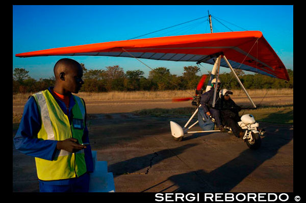 Microlight flights over Victoria Falls. Airstrip and pilots. Viewing the majestic Victoria Falls from above in an open cockpit with the wind in your hair and the sun in your face is an awe-inspiring experience. A microlight flight over the Falls is truly an adventure like no other. It can't be explained. It must be experienced! The "weight-shift" microlights carry a pilot and one passenger. Unfortunately, you won't be allowed to bring your camera, but the Microlights have a unique wing-mounted camera so you'll still be able to take home some amazing pictures in the microlight with the beautiful scenery of the Falls behind you (available for seperate purchase). The 12-15 minute microlight flips ($160) offer an outstanding photographic opportunity to view the full breadth of Victoria Falls, the islands and neighbouring rainforests.  Spray blasts out of the chasm as the full volume of the Zambezi crashes down 108 metres.  The 25-30 minute microlight flights ($320) continue down the Batoka Gorge and include neighbouring wildlife areas in the Zambezi National Park (Zimbabwe) or Mosi-oa-Tunya National Park (Zambia).  Flights take place every day (weather permitting) from dawn to sunset. Minimum age is 6 years, maximum weight is 100kg.