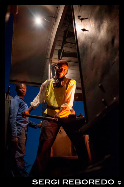 One of the railway workers of the Livingstone Express luxury train charcoal feeding train locomotive.  The Royal Livingstone Express is a unique dining experience combining the luxury of Sun International's Royal Livingstone hotel with the charm of rail travel. The train is an all inclusive luxury rail experience rooted in the nostalgia of a bygone era. Passengers travel leisurely as the sunsets. This is a journey into a timeless world of grace, elegance and romance, where the natural splendor will stir your imagination and the luxurious comfort soothes your soul. This unique luxury rail restoration is an extension of the five-star Royal Livingstone Hotel. The train provides fine wining and dining as you travel through the picturesque Zambezi Valley in Pullman style coaches which have been lovingly restored to their former glory. The Royal Livingstone Express consists of 5 air-conditioned carriages, 2 dining cars, a club/kitchen car, lounge car, and an observation car and is pulled by either a 10th class No. 156 or a 12th class No. 204 locomotive. One of the dining cars, The Wembley, was built by the Birmingham Railway Carriage and Wagon Company, and went on display in London at the British Empire Exhibition in 1924. It was shipped to the Union of South Africa and entered service on 19th May 1926 and hence acquired the name - The Wembley