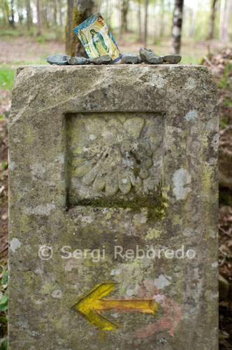 A sign indicates where the pilgrims continue on the road. Signal on a postcard of the Virgin.