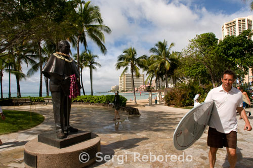 Surfista en la famosa playa de Waikiki. Kalakaua Avenue. O’ahu. Historia del surf Sí, los hawaianos son los fundadores originales del “deporte de los reyes”, que en hawaiano sería “hee nalu”. Luego de la llegada del capitán inglés Cook a las islas, el teniente James King fue el primero en registrar estas inusuales actividades que practicaban los antiguos hawaianos. El Capitán Cook y los demás que no eran hawaianos y que observaban las islas por primera vez, estaban fascinados por la agilidad y dominio de los isleños. Ellos usaban largas tablas talladas de arboles altos para dominar las olas parados con un pie delante del otro o boca abajo, con el cuerpo contra la tabla. El océano con todo su misterio, ia (pez), que da vida y kai (agua), eran muy reverenciados y respetados como componentes esenciales de supervivencia para los antiguos hawaianos. El océano era cuidadosamente estudiado, sus corrientes y mareas eran observadas en detalle; y la pesca, el surf y los viajes eran estratégicamente planeados. El surf no era sólo un divertimento; requería de gran habilidad, energía, flexibilidad y equilibrio. Un hawaiano que pudiera dominar el arte del surf, entre otras habilidades oceánicas, era muy respetado en la sociedad. Los jefes de alta jerarquía (alii), tenían reservados los mejores puntos en cada isla y practicaban con las mejores tablas.