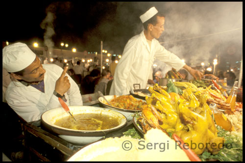 Restaurantes nocturnos en la plaza Djemaa El Fna. Situados en pleno corazón de la ciudad, entre la Plaza Djemaa El Fna  y la Mezquita de Ben Youssef. y diseminados por una miriada de callejones techados, los zocos o mercados nos presentan todo tipo de género en miles de tiendas ajenas al ajetreo que las envuelve. Estos establecimientos, de todo tipo y tamaño, se hacinan unos junto a las otros y así no sería raro encontrar 100 tiendas en 100 metros de calle. En ellas se vende de todo..........Artículos de primera necesidad, babuchas y artículos de cuero, las consabidas alfombras, frutos secos, aceites y cosméticos, joyas y muebles, souvenirs para turistas, telas de todo tipo.....Es difícil pensar en algo que no se pueda encontrar en los Zocos de Marrakech. Además muchos de los tenderos son auténticos artesanos y así tendremos la oportunidad de ver en acción a curtidores, carpinteros, herreros, joyeros, zapateros, cuchilleros o cesteros, fabricar los bienes que abarrotan sus estanterías.