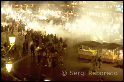 Marrakech. Plaza de Jemaa el Fna. Por la noche Según atardece, la plaza cambia totalmente. Al caer la noche desaparecen los tenderetes de la mañana y se llena de puestos de comida donde poder cenar, músicos improvisados y espectáculos de diferente índole.  Si os atrevéis a cenar en los puestos de la plaza, hay que decir que la comida no está nada mal y los precios son bastante económicos.  Imprescindible Cualquier hora es buena para pasear por Jamaa el Fna y disfrutaréis recorriéndola a diferentes horas.  La plaza está rodeada de tiendas de suvenires, bares y restaurantes. Os recomendamos que entréis a alguno de los bares que cuentan con terraza. Tomarse una consumición por 10 dirhams y ver la vida de la plaza desde las alturas es algo obligatorio.
