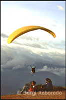 Alguns aficionats s'acosten per veure volar els parapents. Parapent a Terra Negra. Veneçuela. Un a un els parapents van ser descendint per la vall. La suavitat amb que planejaven era sorprenent. Els curiosos s'havien col·locat en llocs estratègics del vessant des d'on es podia divisar tot l'espectacle. Algunes famílies estaven al complet, i els seus fills de poca edat eren els que més gaudien, això sí, sense acabar d'entendre totes les explicacions que els seus pares els estaven donant sobre com un home podia mantenir-se al cel tanta estona sense arribar a caure. Per a les gents de Mèrida aquest idíl·lic paratge resultava una lloc captivador on poder passar l'estona units berenant, mentre les vistes anaven canviant minut a minut com si d'una pel·lícula es tractés.