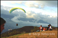 Alguns aficionats s'acosten per veure volar els parapents. Parapent a Terra Negra. Veneçuela. Un a un els parapents van ser descendint per la vall. La suavitat amb que planejaven era sorprenent. Els curiosos s'havien col·locat en llocs estratègics del vessant des d'on es podia divisar tot l'espectacle. Algunes famílies estaven al complet, i els seus fills de poca edat eren els que més gaudien, això sí, sense acabar d'entendre totes les explicacions que els seus pares els estaven donant sobre com un home podia mantenir-se al cel tanta estona sense arribar a caure. Per a les gents de Mèrida aquest idíl·lic paratge resultava una lloc captivador on poder passar l'estona units berenant, mentre les vistes anaven canviant minut a minut com si d'una pel·lícula es tractés.