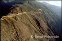 Volant en tàndem. Parapent a Terra Negra. Merida. Veneçuela. La indumentària dels artistes d'aquest esport impressionava en gran manera. Els micos multicolor conjunyien perfectament amb el color de les teles de les seves espelmes. El casc cobria totalment els seus caps, deixant al descobert únicament la circumferència dels seus ulls. Era d'allò més semblant als astronautes que surten a l'espai. L'explicació era lògica, d'una banda el casc era un element clau per a la seguretat i, per altra banda, el mico esmorteïa el vent i les fredes temperatures en l'aire. Tot d'una em vaig veure abillat amb un casc negre al cap, un arnès i lligat mitjançant diverses cordes amb mosquetons a Oswaldo. La tensió era extrema. El parapent, que era d'un color groc llimona, ja estava totalment desplegat. Els seus extrems es movien amb virulència, com si tinguessin pressa per començar a volar.