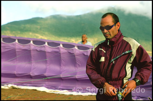 Monitor para vuelos en tandem. Parapente en Tierra Negra. Venezuela. Esa misma tarde salgo del centro de Mérida después de comer. La idea es hacer parapente en una montaña cercana. Después de 45 minutos de tortuoso recorrido, por fin habíamos llegado a Las González o al lugar más comúnmente llamado Tierra Negra. Nadie supo explicarme el porqué de este nombre, pero la cuestión es que la tierra no era ni mucho menos de color negra, sino de un tono rojo cobrizo que contrastaba enormemente con el azul electrizante del cielo. Nos encontrábamos en una enorme planicie a 1700 metros sobre el nivel del mar con unas fabulosas vistas del valle y del río Chama.  l Parapente es una de las principales actividades de aventura que se realiza en Mérida en las González, específicamente sector Tierra Negra, aprox. 40 minutos del casco central de la Ciudad, el vuelo se realiza junto a un instructor profesional, este tipo de vuelo se le conoce como vuelo Tandem y tiene una duración aproximada de 20 a 30 minutos dependiendo de las condiciones del clima, a una altura estimada de 1600Mts  sobre el nivel del mar, Tierra Negra se encuentra entre los 10 mejores lugares del mundo para la practica de este deporte por lo tanto podemos volar de lunes a lunes en las mañanas o en las tardes, es una actividad que puede ser realizada por personas de cualquier edad desde niños hasta adultos, solo se necesita ropa comoda, sueter o chaqueta, zapatos deportivos y comer ligero antes del vuelo. Parapente en Mérida consta con un servicio de transporte desde cualquier punto de la ciudad, casa, hotel, posada, etc… recoge al pasajero o pasajeros y los trae de regreso luego de culminar la actividad….    El costo por persona es de Bs. 360,- con servicio de transporte incluido.
