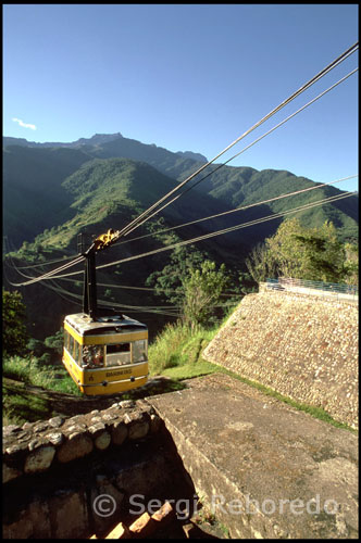 De Loma Redonda a Pico Espejo. Teleférico de Mérida.  Venezuela. El teleférico de Mérida es el más largo y el que mayor altura alcanza en todo el mundo. En la actualidad están realizándose obras de mejora y se prevé que vuelva a funcionar a partir del verano del 2011. Parte de la misma ciudad a 1600m y llega hasta los 4765m, desplazándose en cuatro tramos a lo largo de 12,5 kilómetros. En cada tramo es fácil observar como la vegetación va cambiando paulatinamente, pasando del bosque a la flora típica del páramo para acabar en un paisaje totalmente cubierto por las nieves, a escasos dos kilómetros del Pico Bolívar (5007m), la montaña más alta de Venezuela.  El primer teleférico de Mérida fue proyectado en 1952 por un grupo de andinistas venezolanos llamado el Club Andino Venezolano durante el gobierno del General Marcos Pérez Jiménez, a fin de construir un sistema que facilitara el ascenso a la Sierra Nevada de Mérida. La propuesta fue tomada en cuenta y se procedió a hacer el levantamiento topográfico a fin de desarrollar el proyecto en 1955. Para 1956 se trazó la ruta final y para el siguiente año ya estaba en funcionamiento el teleférico de carga hasta la estación La Aguada, quien serviría de transporte para los materiales necesarios para la construcción de las estaciones. El teleférico fue construido mayormente con apoyo francés, suizo y alemán. Para 1958 el mismo estaba construido en un 50%. La obra se concluyó en marzo de 1960 gracias al apoyo de mano obrera venezolana y del equipo técnico extranjero dirigido por el especialista francés Maurice Comte. La obra tuvo un costo para el momento de su construcción de 70.000.000 de Bolívares que para la época equivalían a unos 16 millones de dólares.