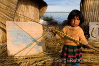 Una niña en la isla de Los Uros ubicada en el interior del Lago Titicaca juega con una caña de totora.