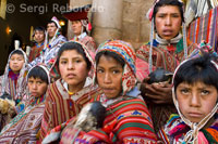 The people of the mountain, dressed in traditional costumes at the door of the church of Pisac Sunday market day. Pisac. Sacred Valley.