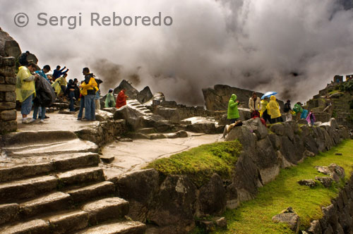 From the "Holy Plaza", towards the northwest is a stairway that rises conducting directly to the " Intiwatana" group, which seen from far away has the shape of an irregular interrupted pyramid that Bingham named "Sacred Hill". It is impressive how the whole sector was adapted to the shape of the natural hill. Surrounding the hill, there are many narrow terraces that are not necessarily farming ones but served in order to stop erosion and protect the "Intiwatana". Almost always those narrow terraces were also used as gardens, that is, with an ornamental purpose; they have no irrigation systems as in the farming ones (excepting the farming terraces in Machupicchu that are in a very humid area making aqueducts unnecessary). Thus, according to their duty, it is possible to identify three terrace types: farming, protective, and ornamental. Before arriving to the top of the hill, on the right side of the stairway there is a ring carved on a rock that is encrusted in the wall; it possibly served in order to support an insignia or flag kept by a spear; old accounts suggest that it was something common in platforms like this. The eastern top of the natural formation was flattened artificially in order to be used as an "Usnu", that is, a special platform from which the Machupicchu chiefs could talk to their people who were standing up on the Main Plaza located in the lower part towards the northeast. The communication was facilitated by the high location of the platform from which there is no interference, and by the sonority reached by human voice that is apparently reflected and amplified when colliding with the opposing terraces. In the central part of that "Sacred Hill" there are vestiges of finely finished buildings with their classical trapezoidal openings; around here, there is an apparently non carved natural rock that is suggested to be a vestige of a Machupicchu model; curiously, the shape of that rock has many coincidences with the local geography. By the top of the hill is the famous carved rock named as "Intiwatana", its shape is irregular (polygonal) finishing with an almost cubic polyhedron on which the top has signs of having been hit. Originally, all the faces of this boulder must have been finely polished; possibly the same way as the Main Temple in Ollantaytambo, that is, it had a smooth surface almost as glass. Moreover, it must have had other auxiliary elements for its use.